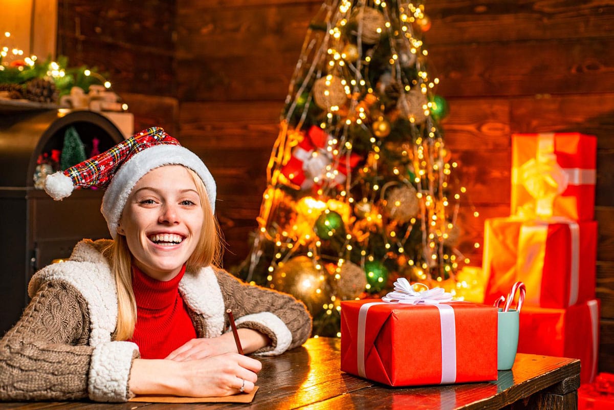 teen girl writing by Christmas tree
